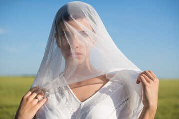 Beautiful young woman playing with veil on a sunny summer day