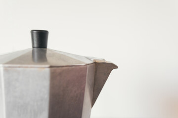 Close up image of a gray metal coffee pot on a white kitchen tile background. Concept of person with coffee needs or freshly prepared breakfast.