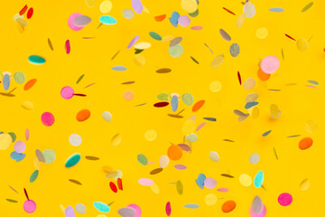 Colorful confetti on yellow background. Copyspace for text. Bright and festive holiday background. - obrazy, fototapety, plakaty