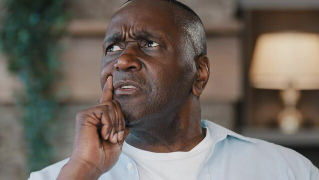 Thoughtful forgetful adult african american man senior middle-aged 60s male pensioner deep in thoughts forget recollect memory create plan thinking come up with idea raises index finger make discovery