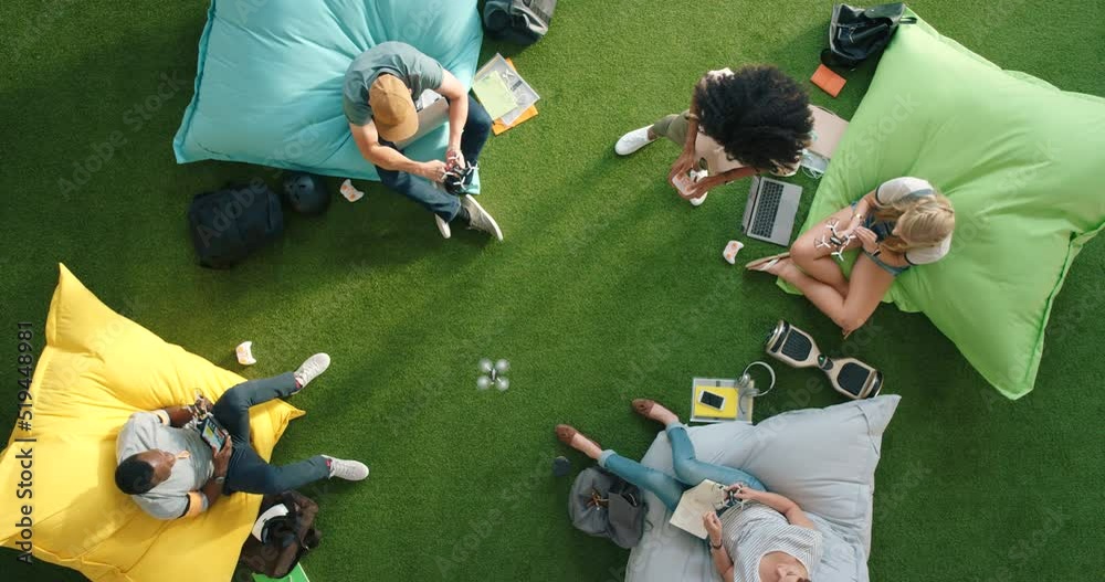 Aufkleber Diverse group of modern technology students using fun room to boost creativity and innovation. Creative team using a drone while relaxing and working on bean bags in an informal office setup