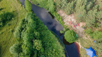 Aerial view of camping with kayaks on the beach of river on a sunny day. Modern kayaks with paddles on beach near river.