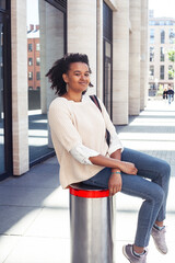 young pretty african girl posing cheerful on city background, lifestyle outdoor people concept