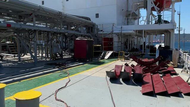 View of the deck of the ship, which is standing near the shore during repairs. The welder is doing the job.