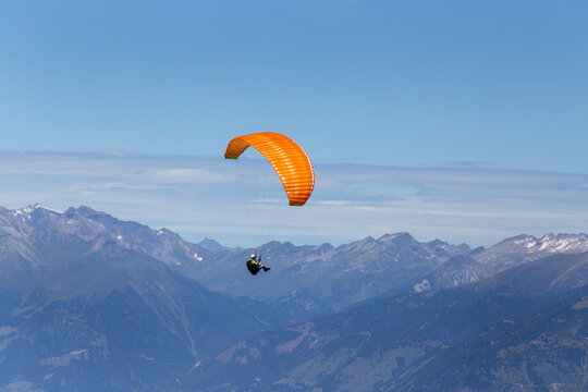 Man with parachute above mountain peaks in Austria