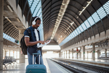 African traveler looking at a map while he is waiting at a train station