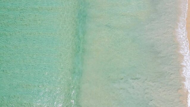 Professional video 4K High angle view Top-down camera over beach sand with seawater Beautiful seawater clear on sandy beach in sunset time.