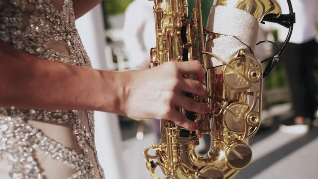 A girl plays the saxophone at an event. Shooting a girl's hands with a close-up tool