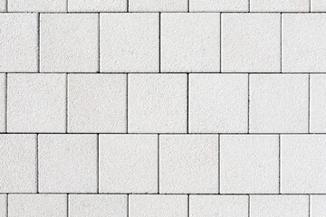 Coating with modern textured paving tiles of square shape. White square paving slabs interspersed...