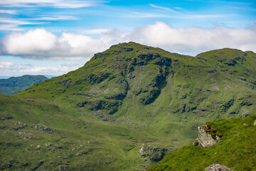 Fototapeta premium View of mountain peaks in the Trossachs National Park from the top of a hill. Beautiful lush green summer mountainous landscape in Scotland