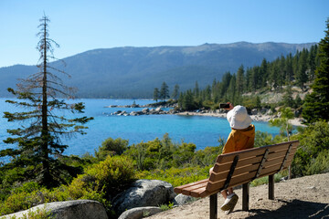 Woman is taking a picture of lake Tahoe sitting on the bench.Traveling and exploring concept