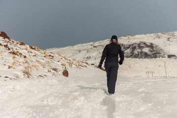woman in black dress walking forward on a snowy road