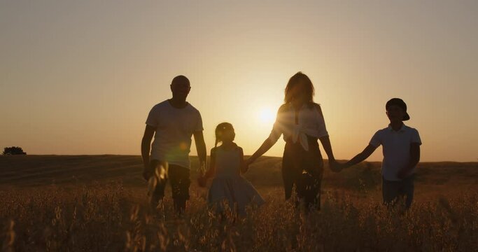 Happy family with children in the field at sunset