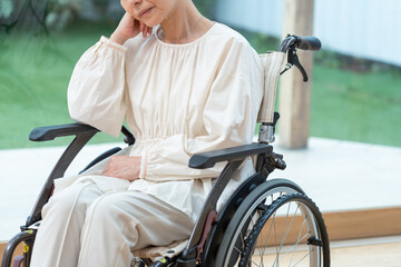 Obraz premium 車椅子に乗った落ち込むシニア女性（介護・怪我）
