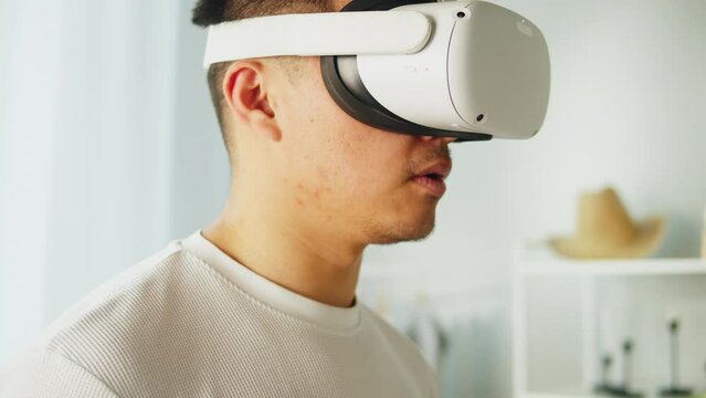 Korean man using virtual reality glasses with controllers, playing video games, Asian guy gamer wearing new generation gaming headset for entertainment at home, future technology concept.