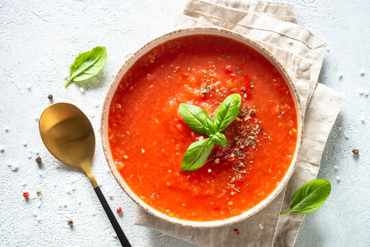 Tomato soup with spices and basil. Cold summer soup. Top view on white background.