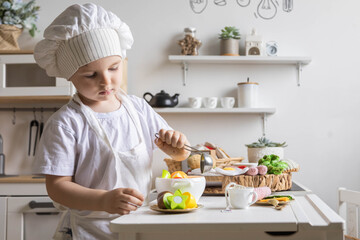 Cute baby boy chef uniform cooking playthings vegetable salad at childish kitchen enjoy childhood