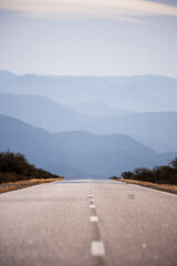 Vertical format photograph of the national highway number 40 with silhouettes of mountains in the background