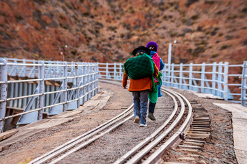 Ladies with backpacks on their backs walking on the train tracks