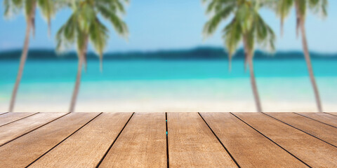 Empty old wooden table in front of blurred background of sand, palm tree and tropical beach background at summer vacation and travel concept with copy space.