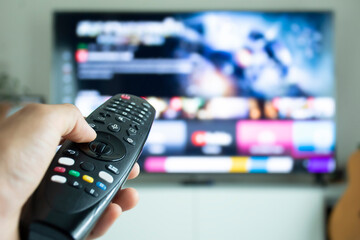 Hand holding a remote to browse TV shows or series.