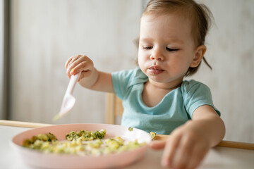 one girl small caucasian child one year old eat at the table at home