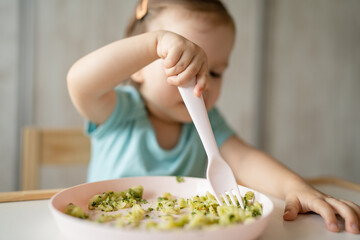one girl small caucasian child one year old eat at the table at home
