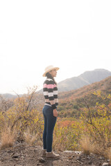 mujer con sombrero contemplando paisaje de montañas