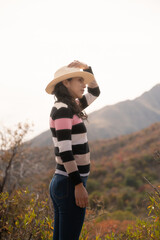 mujer latina con sombrero de paja contemplando y observando las montañas en vacaciones