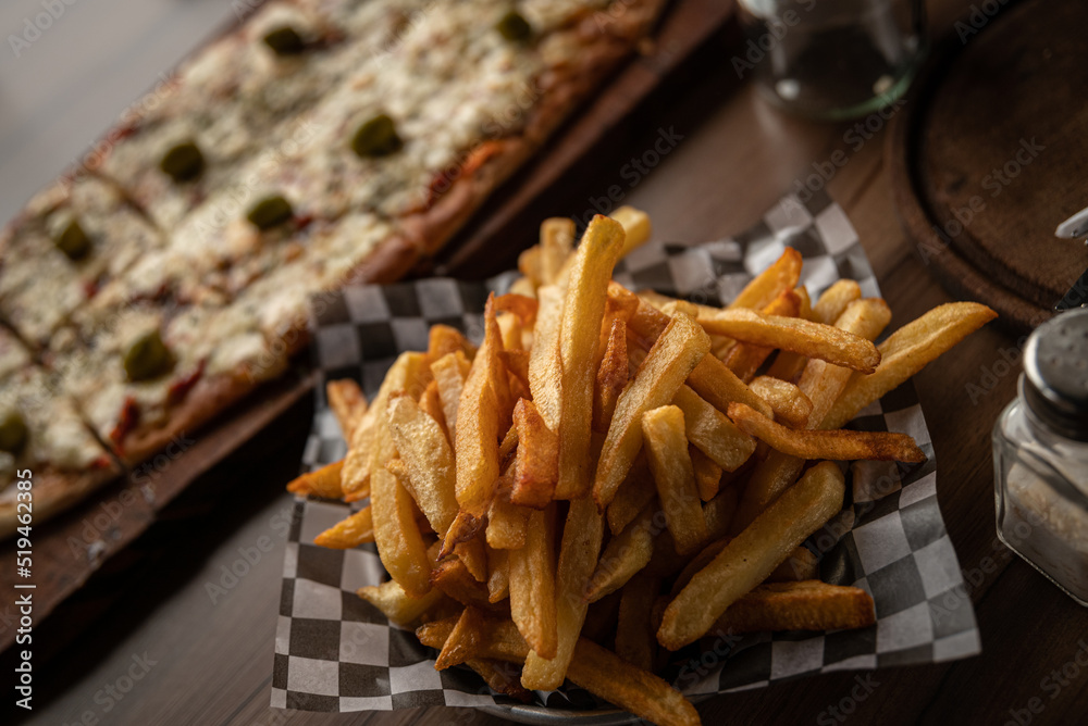 Wall mural pizza crijiente con muzzarella, salsa de tomates, oregano y aceitunas junto a plato de papas fritas