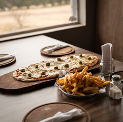 pizza crijiente con muzzarella, salsa de tomates, oregano y aceitunas junto a plato de papas fritas