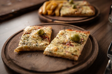 pizza crijiente con muzzarella, salsa de tomates, oregano y aceitunas junto a plato de papas fritas