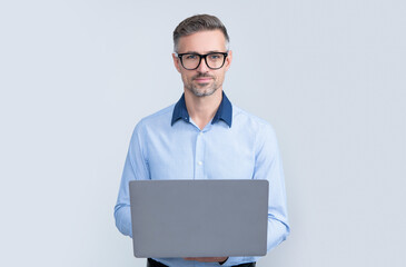 mature manager in eyeglasses working on computer on grey background