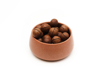 Macadamia nut in a clay bowl on a white background. Shallow depth of field