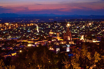 city at night with brigh lights and purpple sky and big parish in san miguel de allende guanajuato 