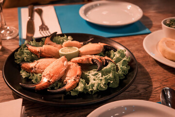 plate of crab claws with lettuce and lemon on a table in an elegant restaurant
