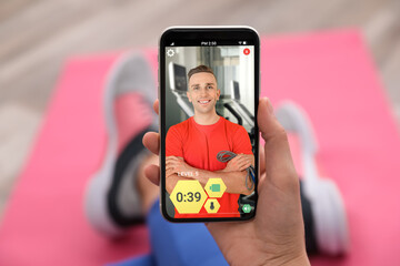Woman having workout with personal trainer via smartphone at home, closeup