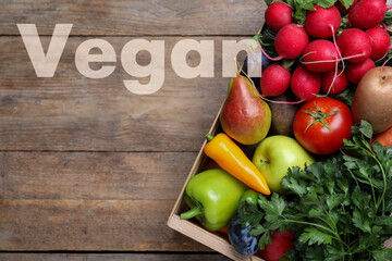 Word Vegan, fresh vegetables and fruits on wooden background, top view