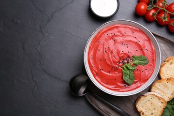 Delicious tomato cream soup with bread on black table, flat lay. Space for text