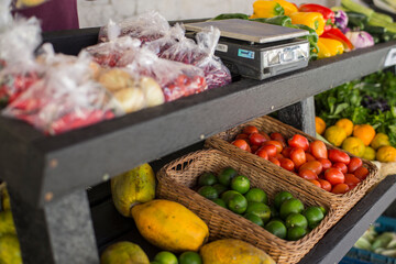 vegetable stand with peppers, tomatoes, eggplants and a scale.
