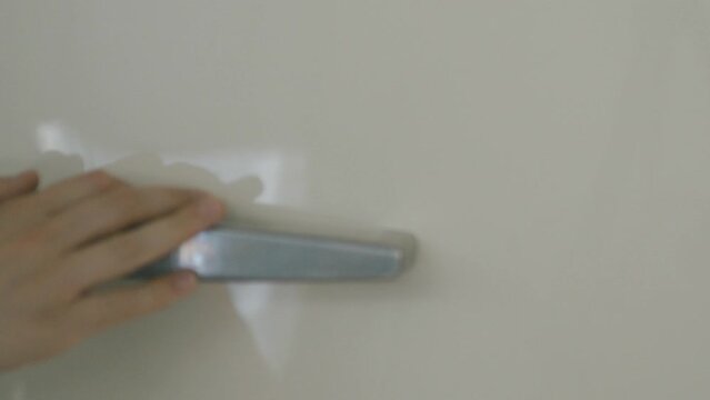 Detail of a hand opening a cream-colored Smeg refrigerator