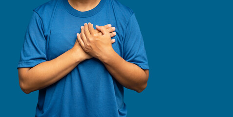 A woman is suffering from chest pain while standing on a blue background