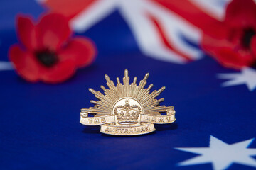 Australian army rising sun hat badge on an Australian flag with red poppies..