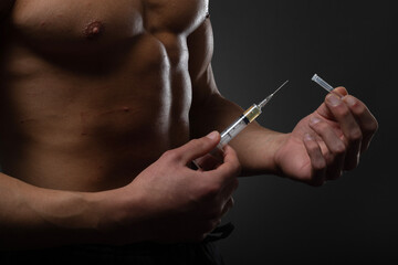 Muscular man with a syringe in his hand. User of anabolic steroids for strength training