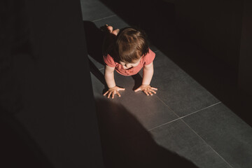 View from above of a baby girl crawling over floor, playing. Baby care. Baby development. Family...