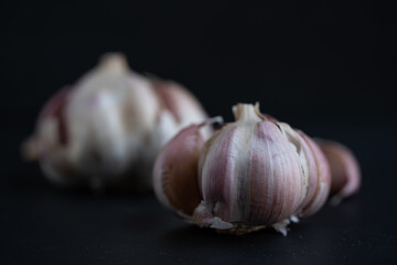 cabezas de ajo, con gajos sueltos sobre fondo negro