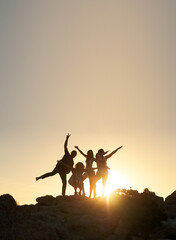 Group of friends posing standing on rocks at sunset having fun summer vacation lifestyle...