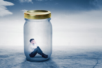 Depressed businessman trapped into a glass jar