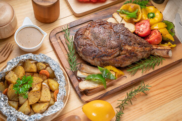 Barbecue Tomahawk Steak on wooden plate.Grilled tomahawk ribeye steak with baked potatoes ,mashroom, roasted sweet peppers and tomato ready to serve. 