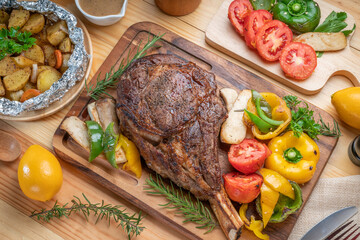 Barbecue Tomahawk Steak on wooden plate.Grilled tomahawk ribeye steak with baked potatoes...